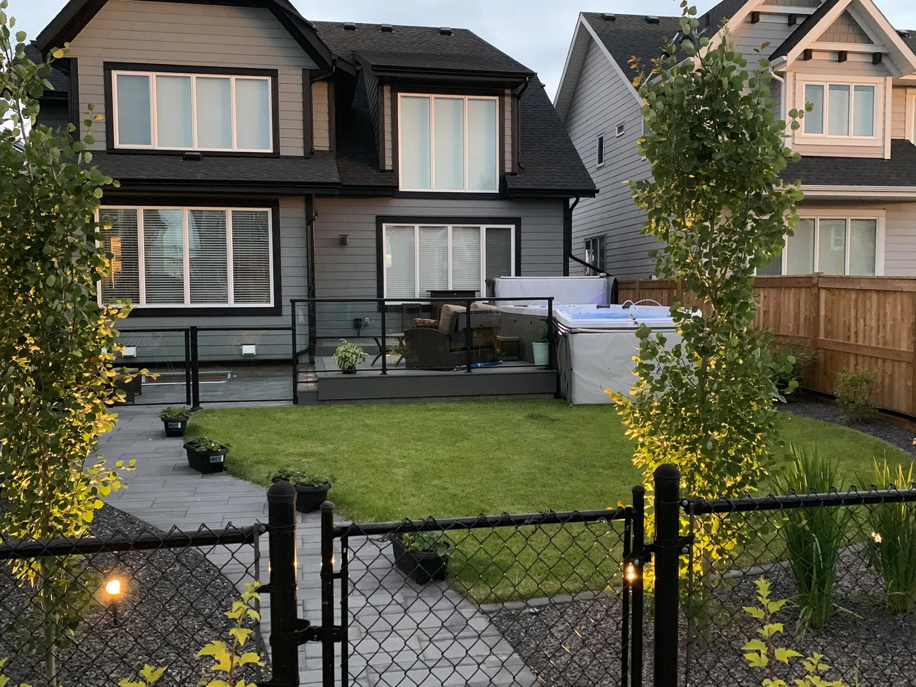Completed Calgary backyard with lawn, paved walkways, deck and integrated landscape lighting